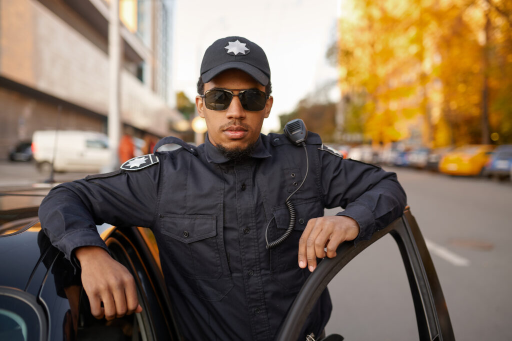 Police officer in uniform poses at the patrol car